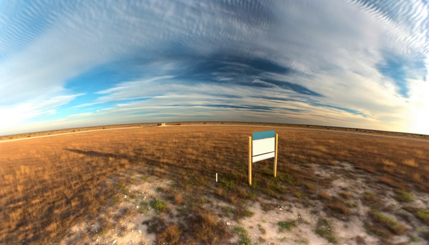 Vacant Texas land parcel with real estate sign at golden hour