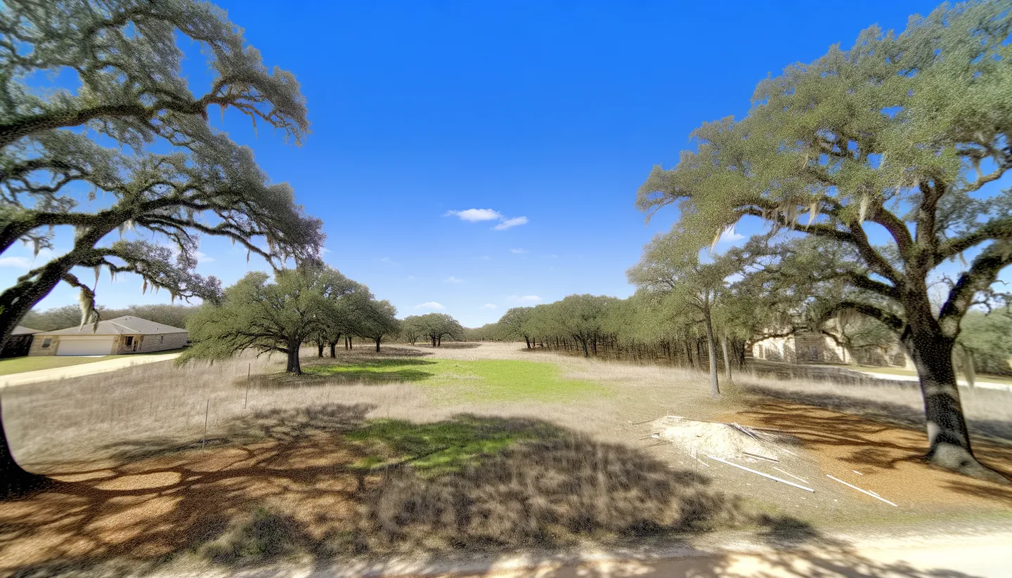 Aerial view of a cleared vacant lot bordered by live oaks in Texas
